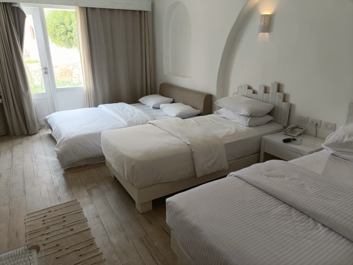 Deluxe room arranged with a double bed and two single beds