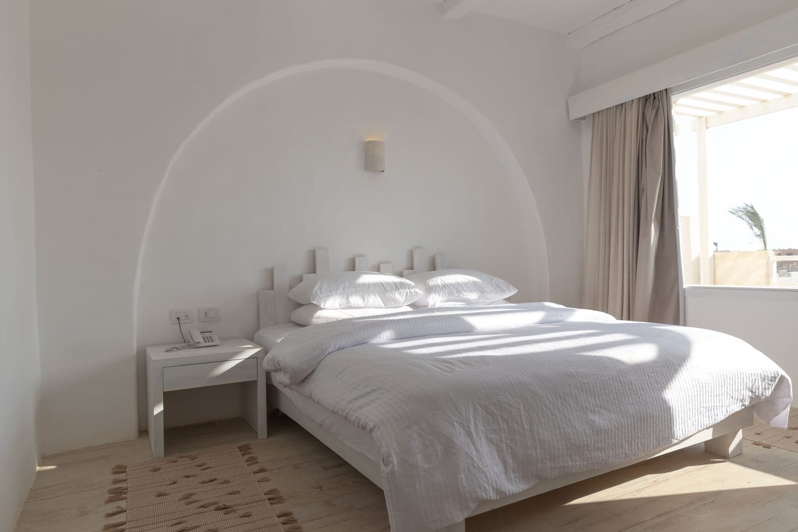Sunlit Standard room double bed beneath an arched headboard