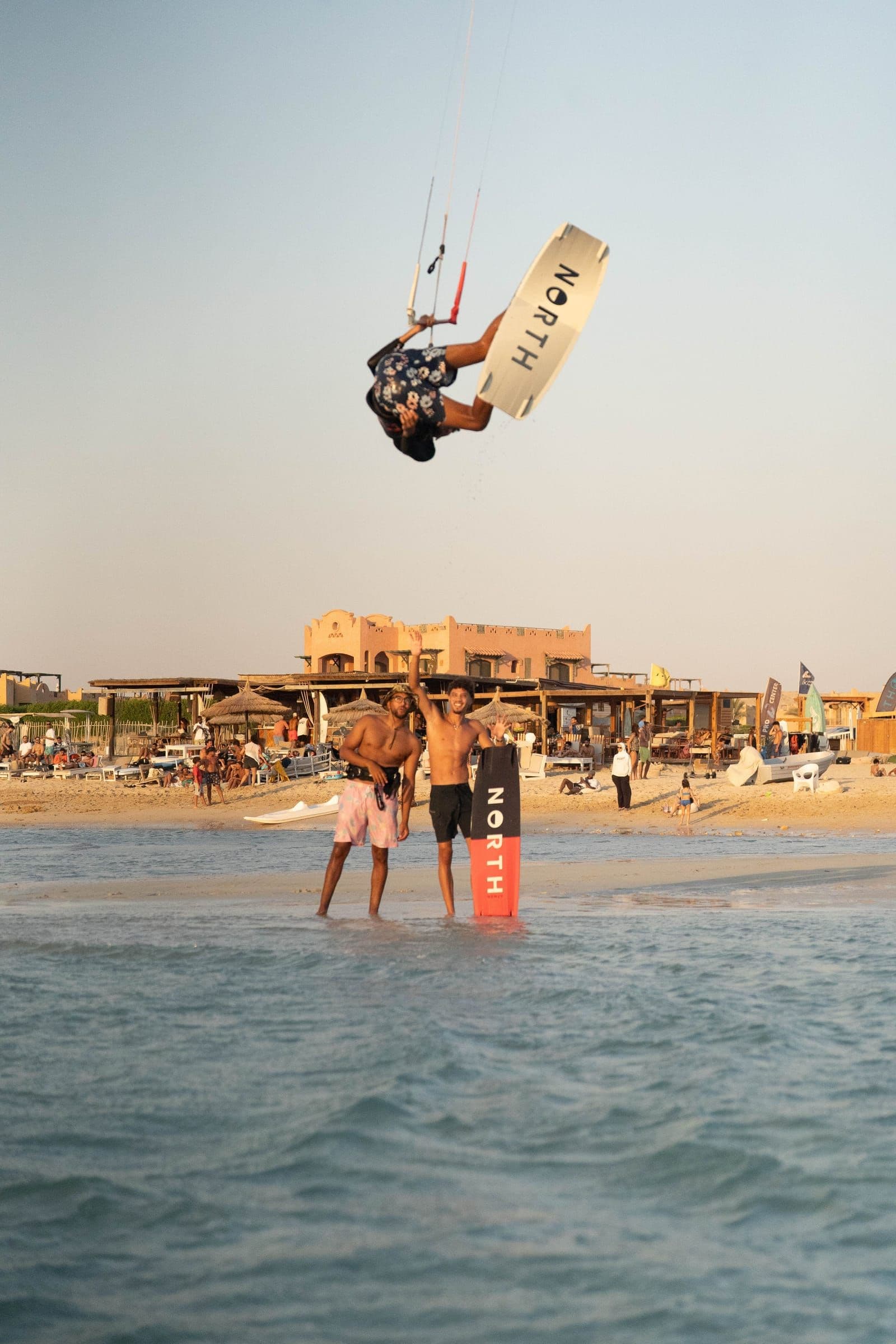Two riders stand in the lagoon as another kitesurfer jumps near the Soul beachfront.