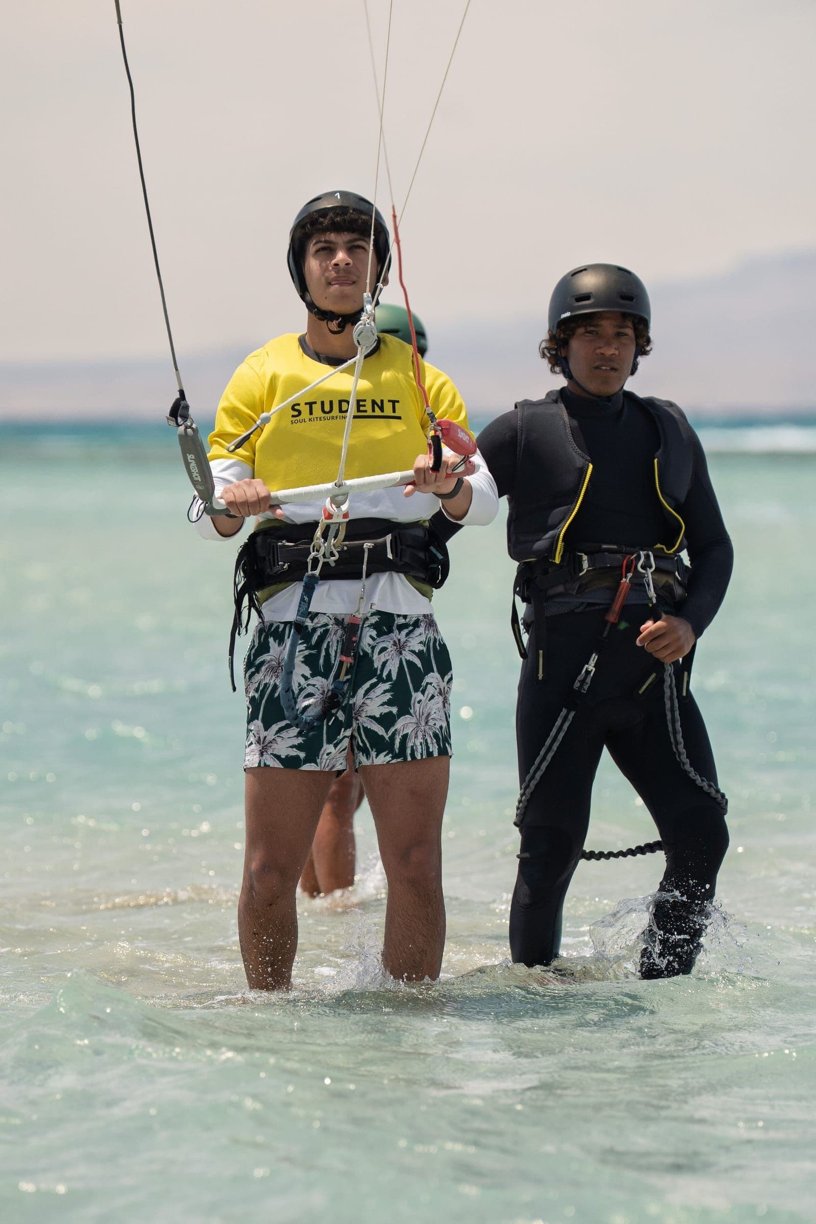 A student holds a kite bar beside an instructor in the lagoon.